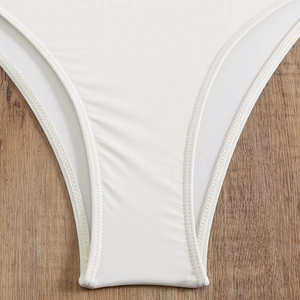 Detail of flat lay white bikini bottom showing double-needle stitching on wood background