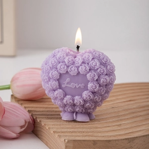 Close-up of heart-shaped purple candle with rose texture and Love text on wood base