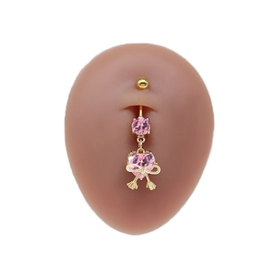 Detail of gold navel ring featuring pink heart gemstone and decorative bow on skin