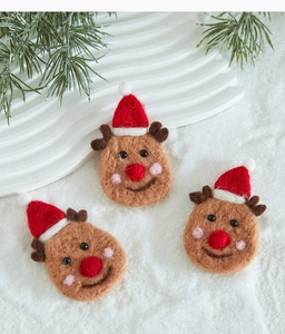 Close-up of three handmade felt reindeer ornaments with red hats for Christmas decor