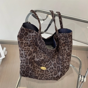 Detailed view of leopard print tote bag with gold logo on a modern transparent chair