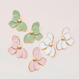 Detailed view of three pairs of enamel flower earrings in green, pink, and white finishes