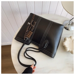 Detail of black leather tote bag featuring white contrast stitching and cute charms