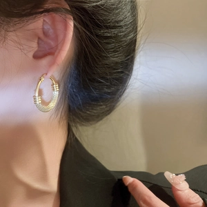 Close-up of textured gold stainless steel hoop earring worn by a model in a minimal style