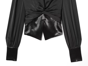 Detailed view of women's black V-neck top with waist knot and satin contrast cuffs