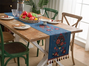 Macro detail of dark blue Christmas table runner with floral patterns and tassel trim