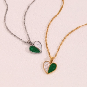 Detailed macro view of heart pendants with green and white split design on twisted chains