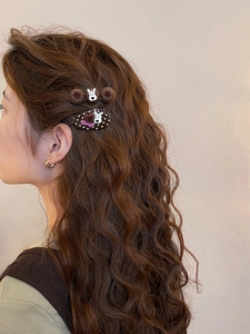 Detail view of brown flocking polka dot hair clip with Zsiga character on wavy hair