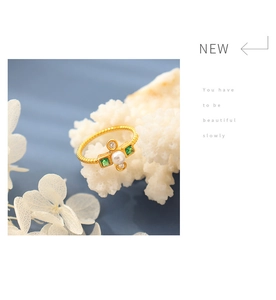 Detail of vintage gold pearl ring with emerald stones and rhinestone accents