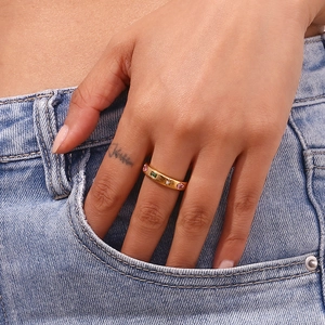 Chic 18K gold-plated wide ring with colorful zircons worn on hand near a denim pocket