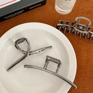 Three minimalist silver metal hair claws featuring twisted knots and square hollow designs