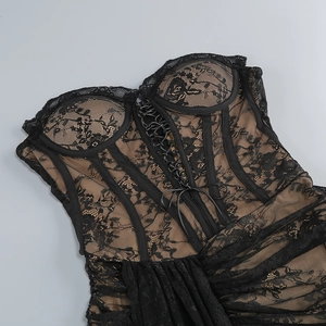 Dettaglio di pizzo floreale nero su fodera sabbia con lacci in stile corsetto