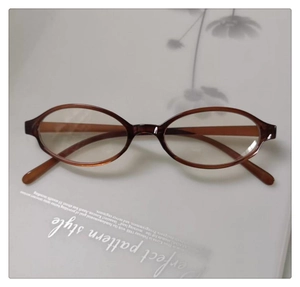 Flat lay of vintage oval tortoiseshell eyeglasses on white surface with plant shadows
