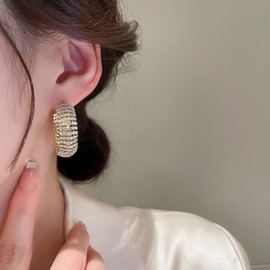 Dettaglio di modella che indossa orecchini a cerchio a C dorati con pavé di strass lucidi