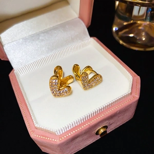 Détail de boucles d'oreilles cœur en or avec zircons sur une boîte à bijoux rose