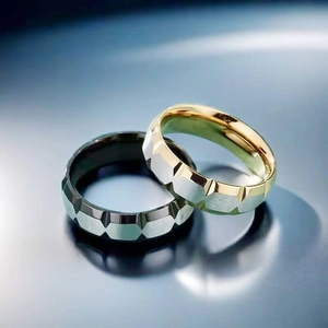 Primer plano de anillos de acero de titanio bicolor con textura de rombos cepillados.