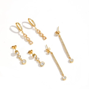 Golden tassel earrings set with drop-shaped and linear zircon stones on white background