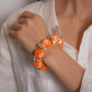 Dettaglio di perle in acrilico marmorizzato arancione vintage con distanziali geometrici oro
