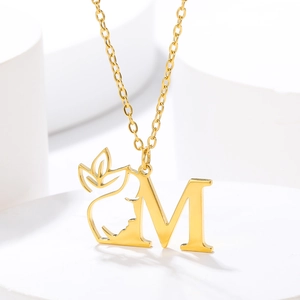 Detailed close-up of golden letter M pendant featuring a feminine profile and leaves