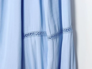Detail van lichtblauwe blouse met geweven stof en opengewerkt geborduurd kant