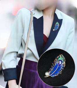 Detail of peacock feather brooch with blue enamel inlay and purple rhinestone on clothing
