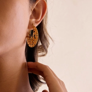 Gros plan d'un mannequin portant des boucles d'oreilles vintage en or 18K avec motif dentelle