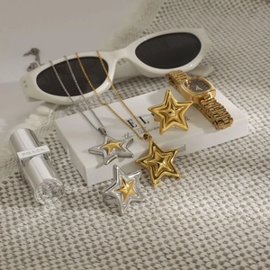 Détail de pendentifs en étoile et bagues ajustables or et argent sur un tissu tissé