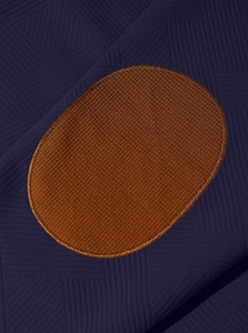 Détail macro du sweat à capuche pour homme montrant le tricot bleu marine et l'empiècement brun