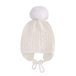 Detailed knit texture of white baby hat with large faux fur pom and ear flaps