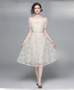Detail eines eleganten champagnerfarbenen Spitzenkleides mit Blumenstickerei und eckigem Ausschnitt