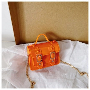 Detail of bright orange jelly satchel bag featuring gold chain strap and dual buckle closures