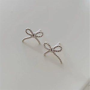 Macro shot of silver bow stud earrings featuring a detailed twisted rope texture design