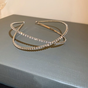 Détail d'un serre-tête croisé argenté orné de strass micro-incrustés sur base métal