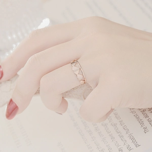 Detail of a rose gold cutout geometric heart ring worn elegantly on a woman's hand