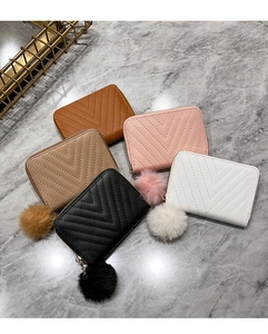 Flat lay of quilted leather wallets in five colors with matching fur ball charms