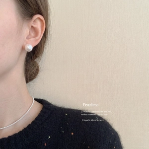 Elegant pearl earring and necklace set worn by a model in a sophisticated studio setting