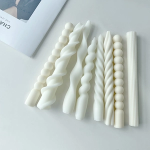 Detailed view of eight assorted spiral and ribbed white pillar candles on a white surface