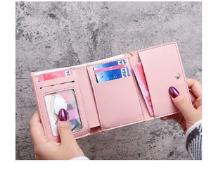 Detail of pink tri-fold wallet showing multiple card slots and secure snap closure
