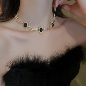 Close-up of vintage gold double-layer necklace with black oval gemstones on a model