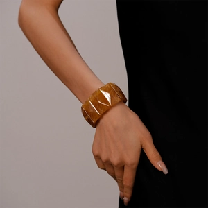 Detailed view of an amber acrylic geometric bangle with smooth resin texture on wrist