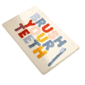 Plush bathroom mat with Brush Your Teeth text and toothbrush pattern on beige base