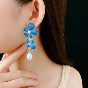 Close-up of vintage blue enamel flower earrings with pearl drops worn by a model