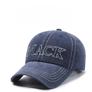 Dettaglio del ricamo MACK bianco e cuciture a contrasto sul berretto di cotone blu scuro