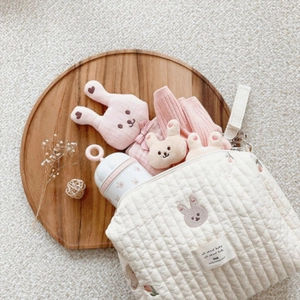 Close-up of quilted cotton nursery bag with cute rabbit embroidery on a wooden tray