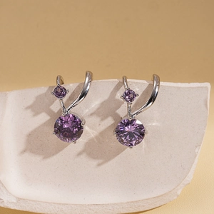Double-layer zircon geometric ear cuffs with purple stones on white marble background