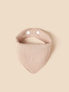 Detail of soft light brown cotton muslin baby bib showing fabric texture and snap buttons