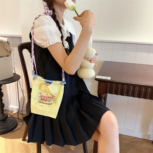 Detailed embroidery on bright yellow mini drawstring bag with purple woven strap