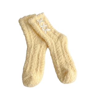 Soft yellow fuzzy coral fleece socks with cute white bow accents for winter warmth
