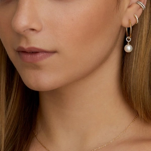 Close-up of elegant S925 silver pearl earrings and cross chain on a female model