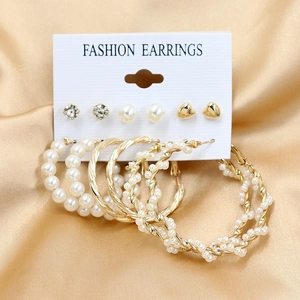 Détail de six paires de boucles d'oreilles dorées avec perles sur fond de soie